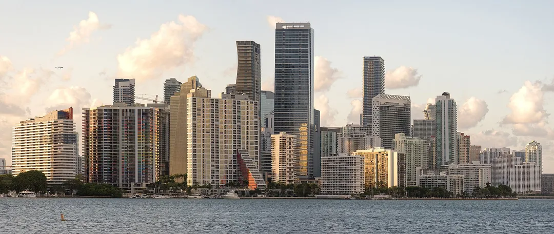 Closely spaced waterfront high-rises in Florida beneath sunlit clouds.