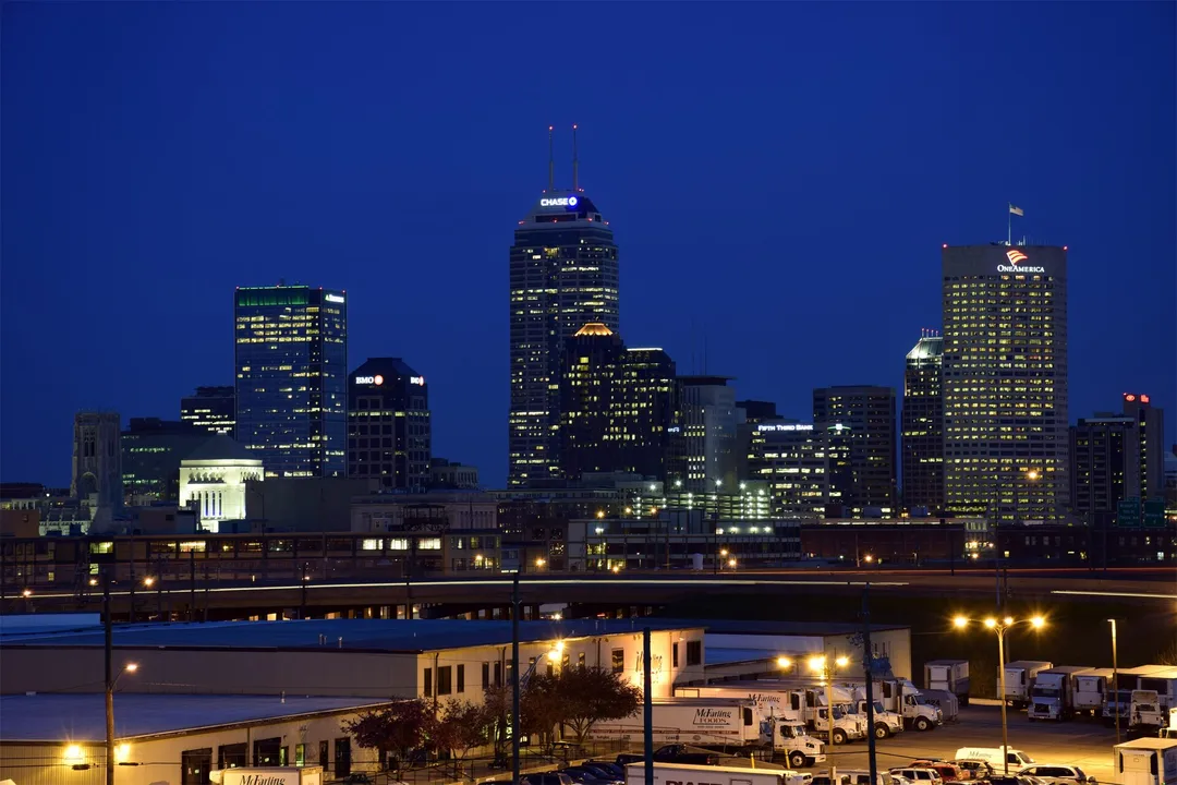Illuminated downtown towers in Indiana beneath a deep blue evening sky.