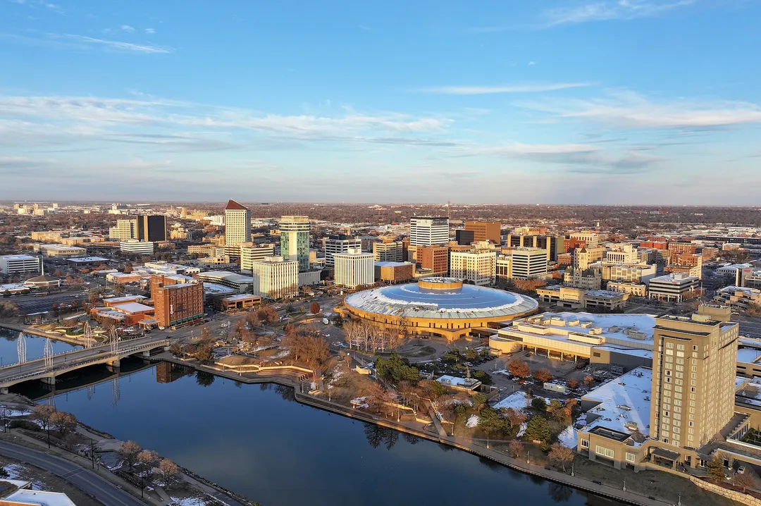 Aerial view of a river, downtown buildings and a circular-roofed complex in Kansas.