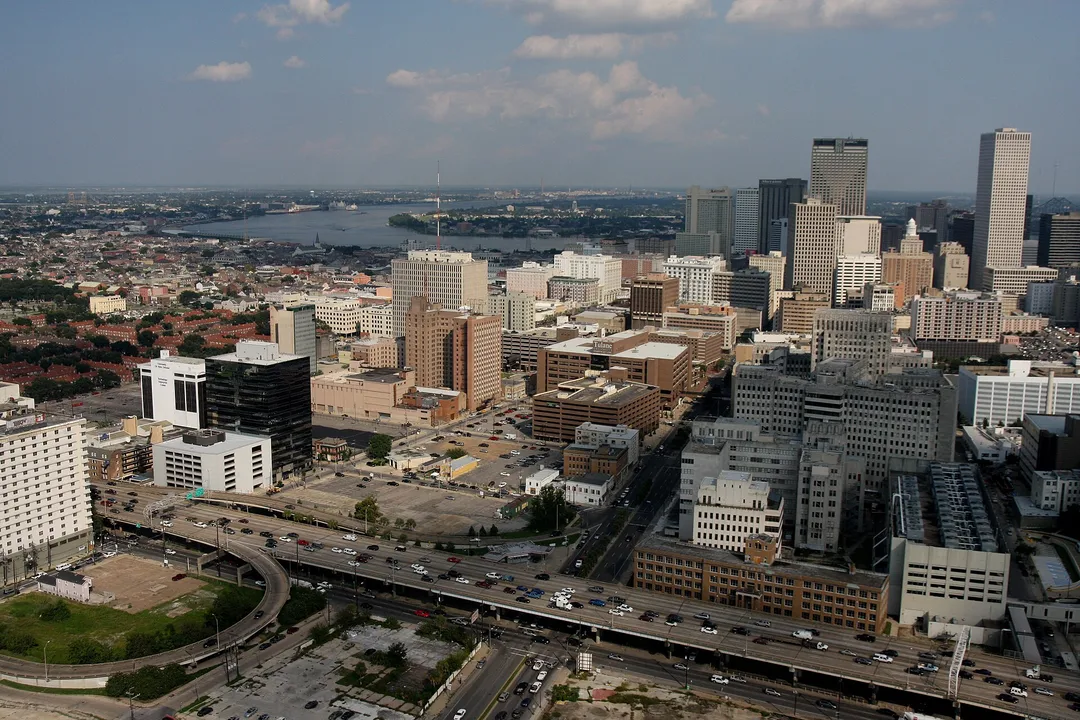 Aerial view of Louisiana city blocks, highways and high-rises near a broad river.
