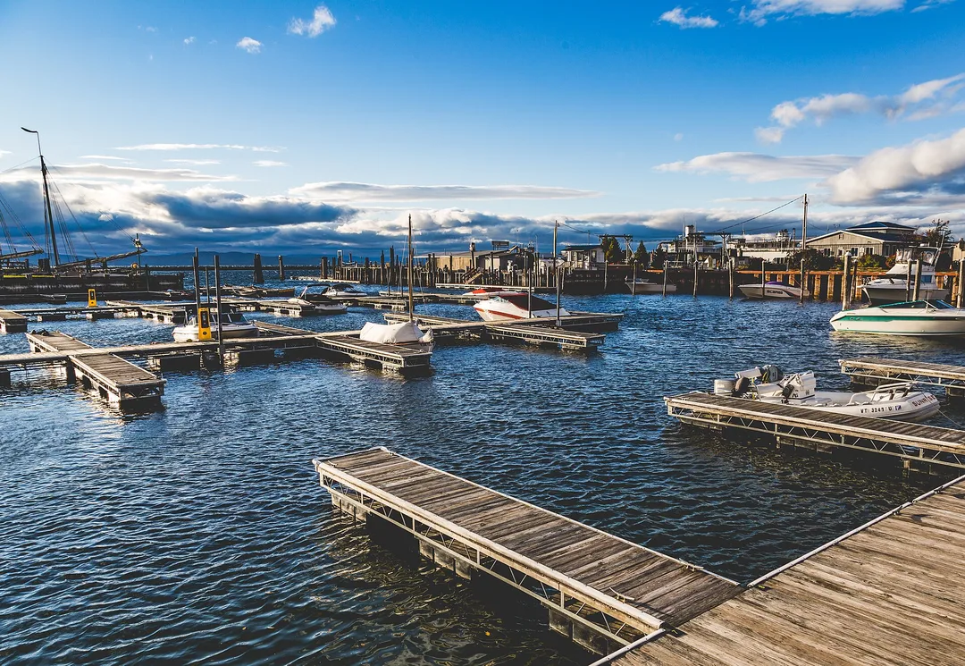Floating docks and sailboats fill a Vermont marina beneath a distant ridge and low clouds.
